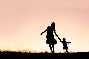 Silhouette of Mother and Baby Daughter Running and Dancing at Sunset